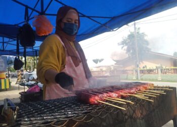 NORSHAFINA Mohamad membakar tongmo di gerainya di pantai Sungai Tuang di Masjid Tanah, Melaka. - UTUSAN/MUHAMMAD SHAHIZAM TAZALI