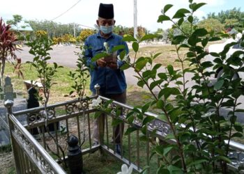 KAMARUDIN Sarip menziarahi pusara Allahyarham Hasni Hardi Parlan dan membantu mengambil gambar untuk ditatap waris dan kenalan mangsa di Tanah Wakaf Perkuburan Paya Luas, Batu Anam, Segamat di Johor. -UTUSAN/FARAHWAHIDA AHMAD